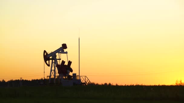 Producción de combustible, bomba de aceite, aceite de bombeo en campo en contraluz del atardecer. — Vídeo de stock