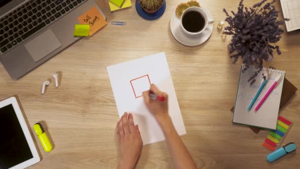 Mädchen stützt Bild eines intelligenten Hauses sich auf ein Blatt Papier, sitzt am Arbeitstisch, First-Person-Ansicht der Hände. — Stockvideo