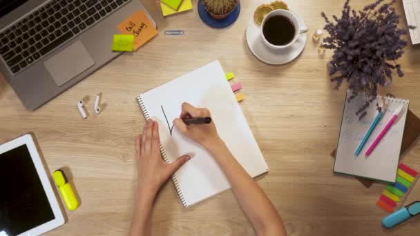 Chica escribe en un papel una frase - aprender español, sentado en la mesa de trabajo, vista en primera persona de las manos. — Vídeo de stock