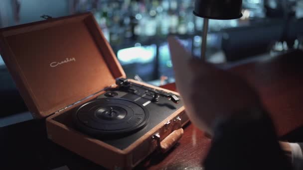 Belarus, Minsk - September 4, 2017: Bar counter in the pub, man sets the record on the vinyl player and turns on the music. — Stock Video