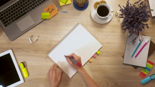 Menina escreve em um pedaço de papel uma frase - reativa, sentado à mesa de trabalho, visão em primeira pessoa de mãos. — Vídeo de Stock