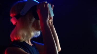 Sarışın kız bardaklarda sanal gerçeklik, renkli neon aydınlatma, fütüristik beyaz Vr gözlükler.