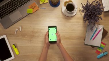 Kız el smartphone ile yeşil ekran, swiping ve dokunun iş masadan, birinci şahıs bakış ekranında, tutar.