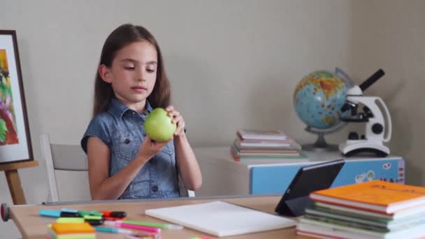 Skolflicka leker med äpple, skola interiör på bakgrund. — Stockvideo