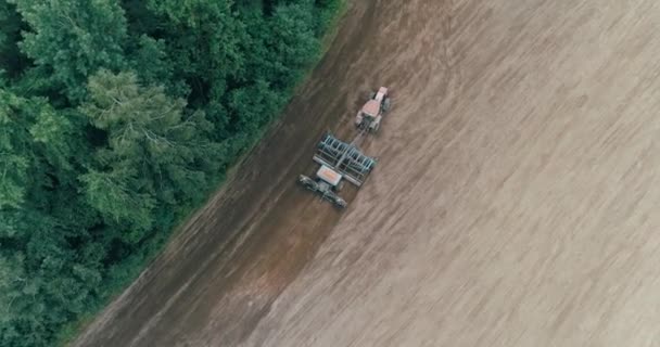 Platteland en landbouw, graan zaaien, boerderij Tractoren ploegen de aarde in veld uitzicht vanaf hoogte. — Stockvideo