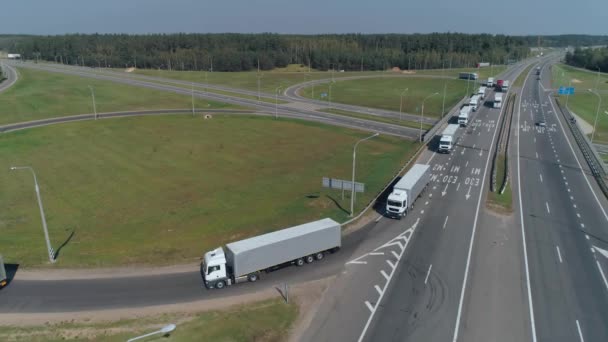 Comboio de caminhões de passeio na rodovia, a junção de estrada perto de floresta, transporte logístico, vista da estrada de altura. — Vídeo de Stock