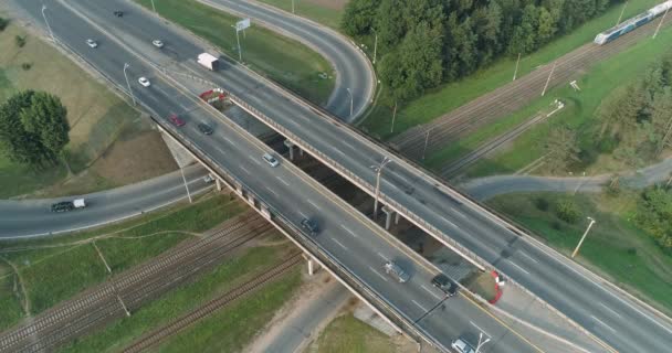 Dálnice v blízkosti železnice, nákladní vlakem na železniční, automobilové dopravy na silniční křižovatku, pohled z výšky. — Stock video