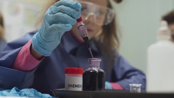 Laboratorio, un scoolgirl en gafas de protección vierte líquido en tubo de ensayo, experiencia química, Educación de los niños. — Vídeos de Stock