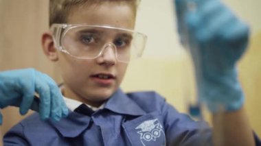 Laboratuvar, bir scoolboy koruyucu gözlük bir sıvı bir cam şişeye, kimyasal deneyim, çocuklar eğitim inceliyor..