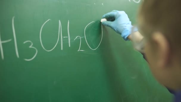 Урок хімії, школяр пише хімічну формулу крейдою на дошці . — стокове відео