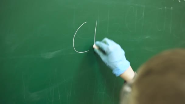 Kemi lektion, en skolpojke skriver en kemisk formel i krita på en svart tavla. — Stockvideo