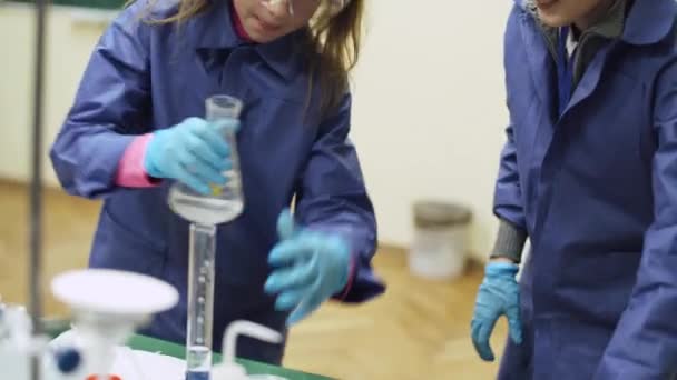 Labor, ein Schulmädchen und Schuljungen in Schutzbrille gießt Flüssigkeit in Reagenzglas, chemische Erfahrung, Ausbildung der Kinder. — Stockvideo