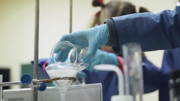 Laboratorium, een schoolmeisje en schooljongen in beschermende bril giet vloeistof in de reageerbuis, chemische ervaring, onderwijs kinderen. — Stockvideo