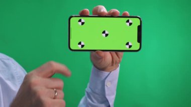 Erkekler kullanma smartphone chromakey içinde tokatlamak ekranında, bir fotoğraf ve tıklama tablet ekranında, yaşasın arka plan yeşil.