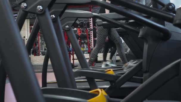 Spor salonu, aerobik egzersiz bir koşu bandı üzerinde yürüyen kadın atlet. — Stok video