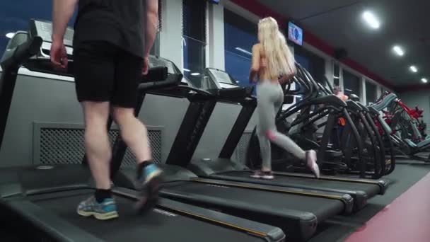Беларусь, Минск - 13 ноября 2018: Тренажерный зал, мужчина и девушка спортсмен, работает на беговой дорожке, аэробные упражнения. — стоковое видео