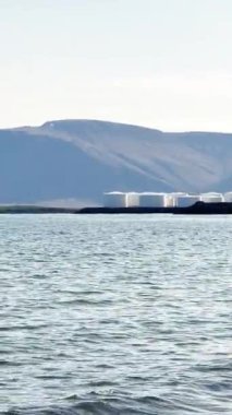 Deniz manzarası, dev beyaz tanklar, petrol ve yakıt depolama tesisleri, ufuktaki dağlar, endüstriyel İzlanda manzarası..