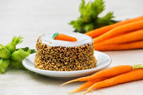 small carrot cake with fresh carrot and fresh green hazelnuts in white teler on wooden table