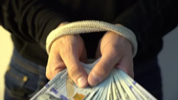 Чоловіча рука пов'язана з мотузкою, що тримає купу грошей банкноти американського долара, концепція фінансових рецидивів — стокове відео