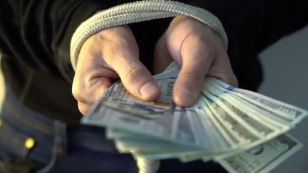 Mano masculina atada con la cuerda que sostiene la pila del dinero billetes de banco americanos del dólar, concepto de las rectricciones financieras — Vídeo de stock