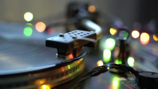 O disco de vinil no DJ toca-discos de perto. A placa rotativa e o estilete com a agulha de perto. Loop. brilhando bokeh luzes festivo humor feriados conceito — Vídeo de Stock