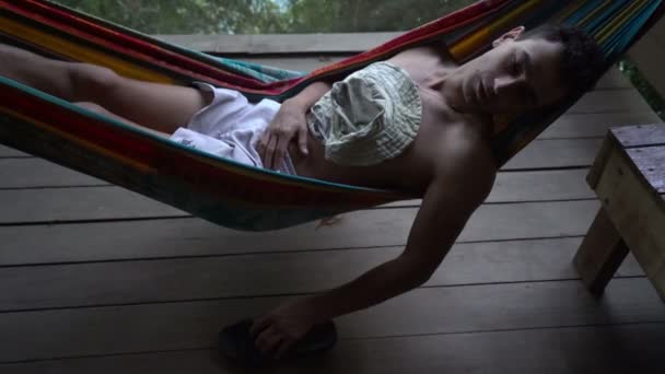 Человек в гамаке лежит в одиночестве брошенный и сходит с ума отвлекаясь, одиночество психически больным — стоковое видео
