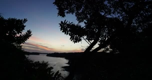 Hermoso lapso de tiempo de puesta de sol con árboles, el sol entra en el océano, sobre el agua, el cielo se vuelve rojo — Vídeos de Stock