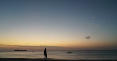 kadın silhuette tek başına ayakta ve tropik sahilde günbatımı, felsefi kavramı dört gözle