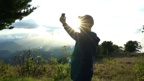 El hombre tomando selfies en las montañas cuando sale el sol hermoso paisaje. Recuerdos de vacaciones — Vídeos de Stock