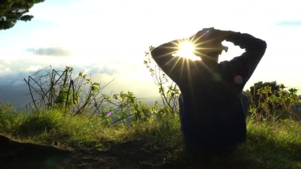 Mann Einsiedler trifft Sonnenaufgang am Rande der Berge. Meditation im Sonnenlicht. — Stockvideo