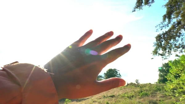 Main féminine toucher la lumière du soleil — Photo