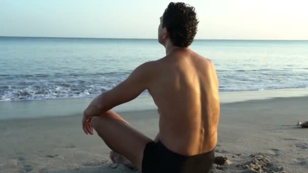 Joven hombre caucásico relajándose en la playa cerca del mar tranquilo, primer plano de las manos, gyan mudra y loto — Vídeos de Stock