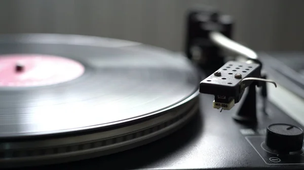 De vinyl record op Dj draaitafel platenspeler close-up. De roterende plaat en de naald met de — Stockfoto