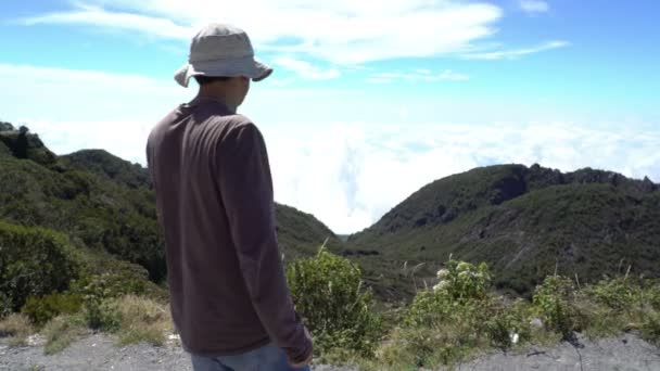 Llegando a la cima. El hombre llega al punto de vista mirando a su alrededor por encima de las nubes. Hermosa inspiración — Vídeos de Stock