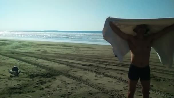 Человек на пляже держит полотенце. Концепция путешествий, клип воспоминаний — стоковое видео