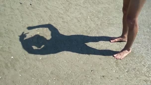 Man op het strand spelen met zijn schaduw op het zand, boos van nietsdoen in ongewone betaalomgeving — Stockvideo