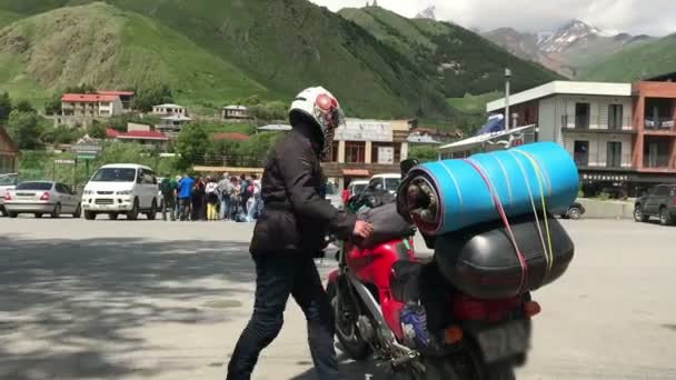 Kobieta rowerzysta siedzieć na motocyklu, turystyka turystyczna, w środku gór Gruzji, Kazbek widok — Wideo stockowe