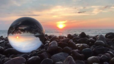 Taşlar üzerinde kristal top içinde Beutifull günbatımı yansıması, su üzerinde güneş, plaj, manzara