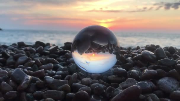 Красивое отражение заката внутри хрустального шара на камнях, солнце над водой, пляж, пейзаж — стоковое видео