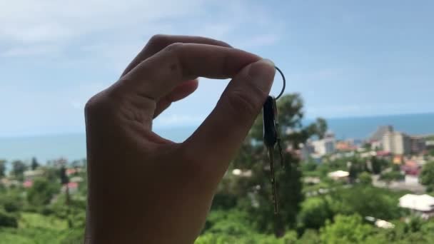 Mão feminina segurando chave do hotel no fundo bonito seaview, conceito de viagem — Vídeo de Stock