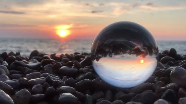 Paysage arrière-plan béatifique à l'intérieur boule de cristal reposait sur des pierres de plage, coucher de soleil et vagues océan à l'intérieur — Video