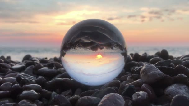 Βρόχο σινεμά κρυστάλλινη σφαίρα στην παραλία πέτρες ηλιοβασίλεμα, υπέροχο τοπίο — Αρχείο Βίντεο