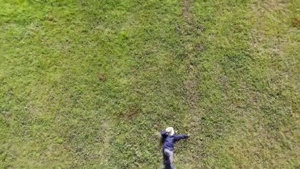 Vogelperspektive eines kaukasischen oder hispanischen Mannes, der sich an einem sonnigen Tag auf das grüne Gras legt — Stockvideo