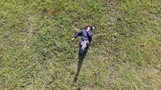 Bird eye view shot van een blanke of Hispanic man die op een zonnige dag op groen gras neerlegt — Stockvideo