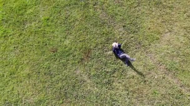 Vogelperspektive eines kaukasischen oder hispanischen Mannes, der sich an einem sonnigen Tag auf das grüne Gras legt — Stockvideo