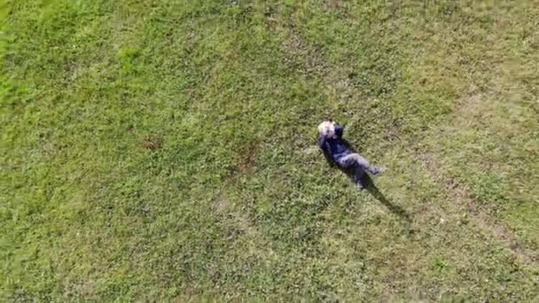 Visão de olho de pássaro tiro de um homem caucasiano ou hispânico que estabelece na grama verde em um dia ensolarado — Vídeo de Stock