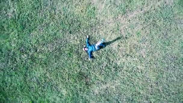 Vista de pájaro de un hombre caucásico o hispano acostado sobre hierba verde en un día soleado — Vídeos de Stock