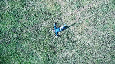 Güneşli bir günde yeşil çimenlerin üzerine yatan beyaz ya da İspanyol bir adamın kuş bakışı görüntüsü