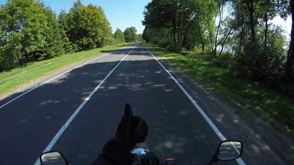 Beyaz Rusya'da güzel bir manzara doğal ve boş orman yolda Motosikletçi Rides ve başparmak göstermek Telifsiz Stok Fotoğraflar