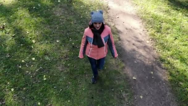 Молодая красивая женщина прогуливается по деревьям в осеннем парке, снимок с воздуха, видео с беспилотника — стоковое видео